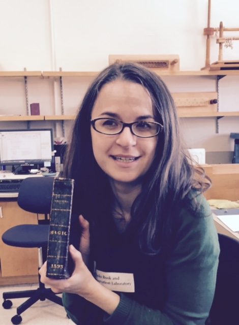 Book and Paper Conservator Christina Amato holds Demonomanie des Sorciers.