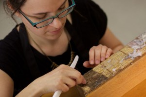 Christina Amato, cleaning old glue from the spine of a book. 